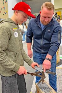 Lars Schinowski (r.) erklärt einem Schüler die Arbeit mit Schieferschindeln.