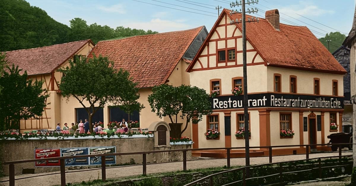 Historische Postkarte aus den Anfangsjahren: Die „Gemütliche Ecke“ als „Gasthaus M. Nett“ in Adenau, vermutlich Ende der 1920er-Jahre. Schon damals trug das Haus den Namen „Restaurant zur gemütlichen Ecke“. Nachträglich, mit Hilfe von KI koloriert